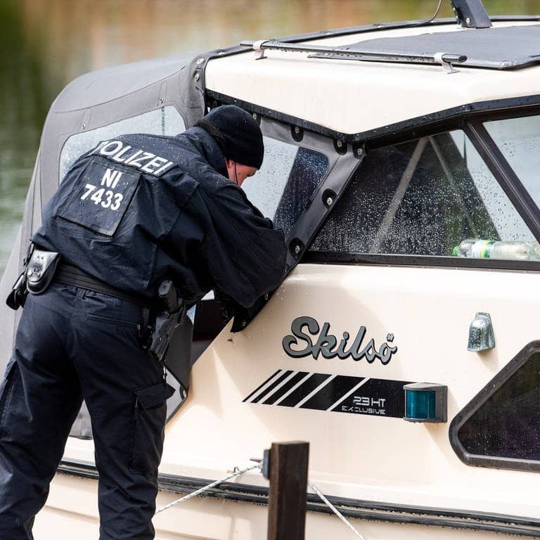 Ein Polizist schaut auf der Suche nach einem vermissten Jungen an einem Anleger an der Oste in ein Boot. (Foto: dpa Bildfunk, picture alliance/dpa | Daniel Bockwoldt)