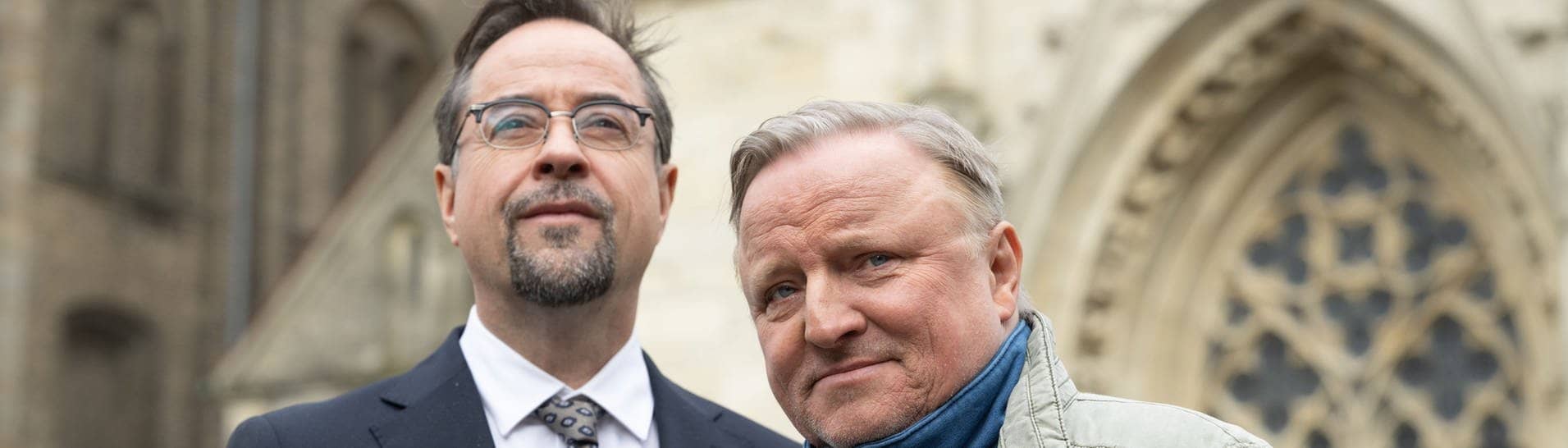 Tatort Münster: Die Schauspieler Jan Josef Liefers (l. Prof. Karl-Friedrich Boerne) und Axel Prahl (als Kommissar Thiel) stehen bei einem Fototermin vor der Liebfrauen-Überwasserkirche.