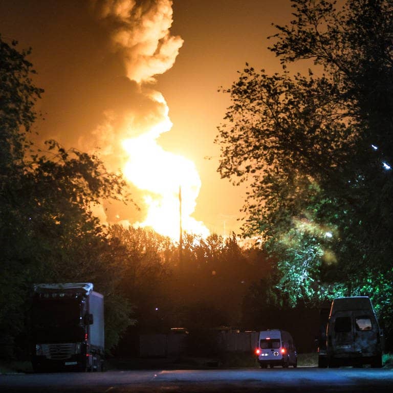 Eine Flamme sticht in den nächtlichen Himmel hinter Bäumen in Luhansk (von Russland besetztes Gebiet in der Ukraine).