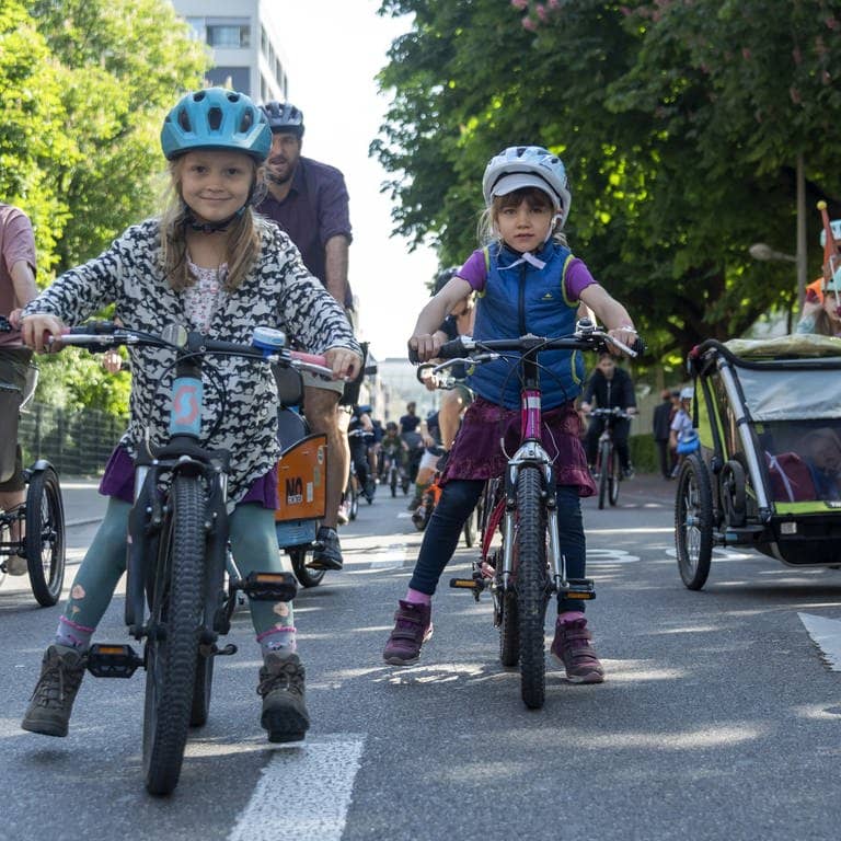 Kinder fahren mit ihren Eltern auf der Straße mit ihren Fahrrädern