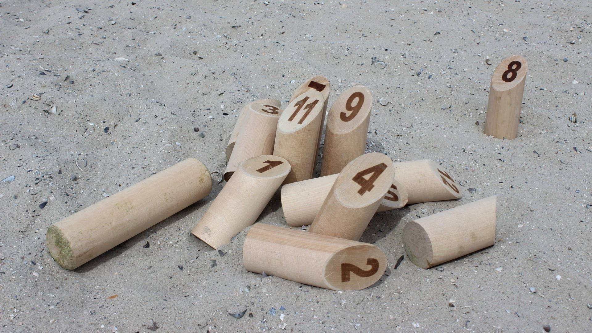 Nummerierte Holzklötze liegen im Sand