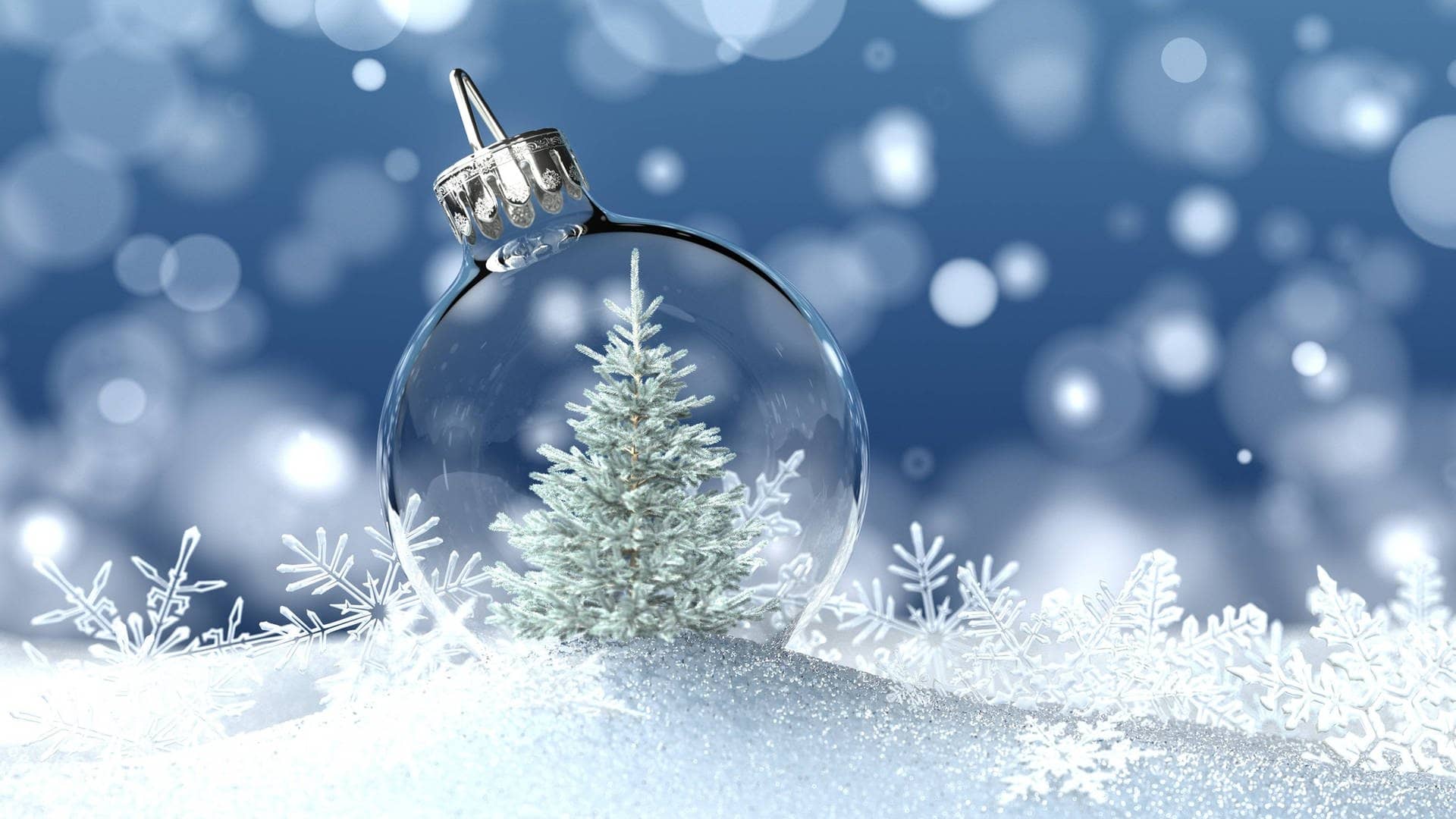 Weiße Weihnachten: Schneekugel mit Weihnachtsbaum und Eiskristallen liegt auf Schnee.