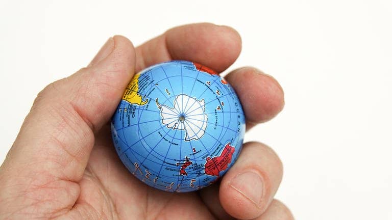 Ein Globus in der Hand zeigt die Antarktis und den Südpol
