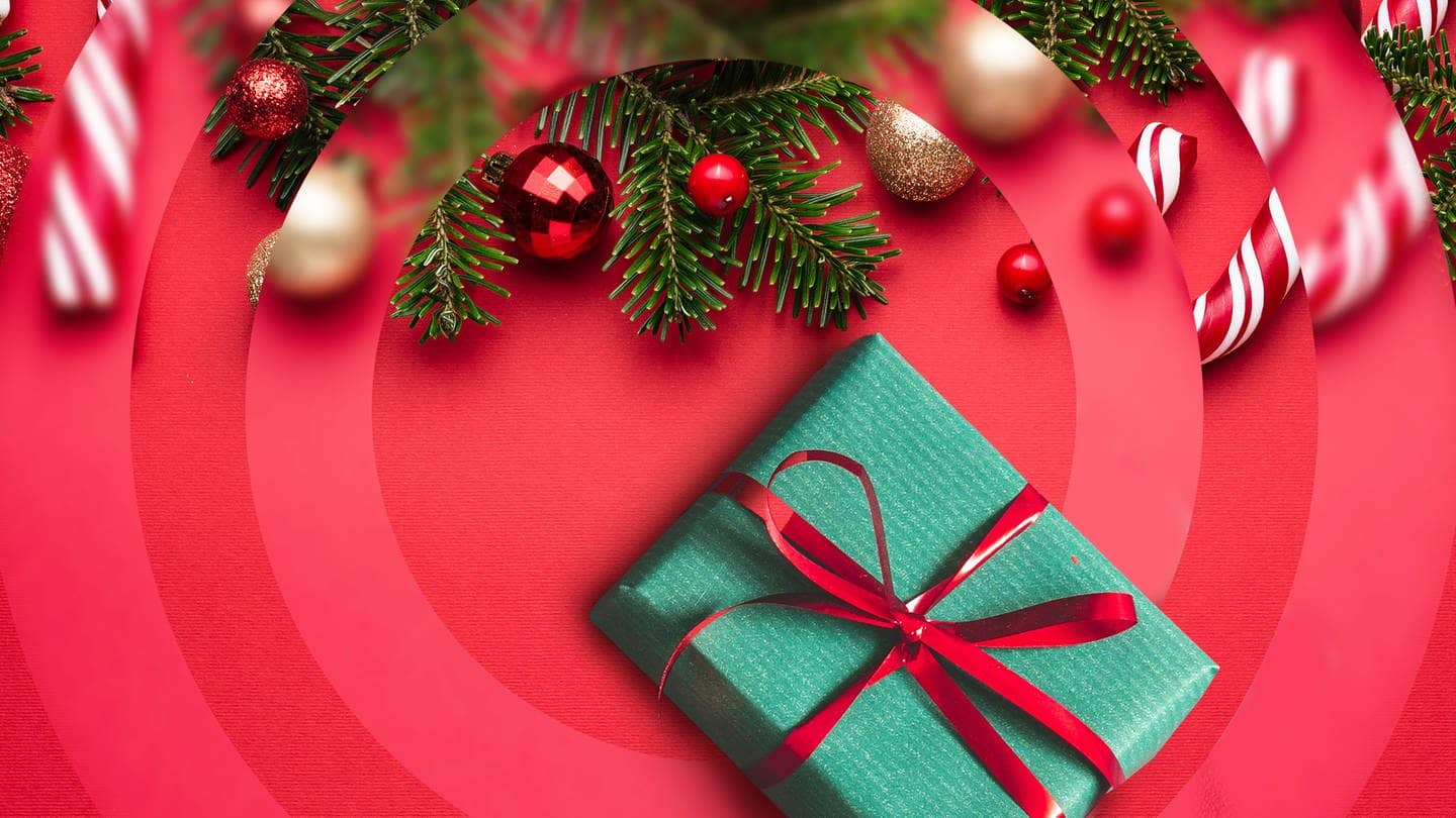 Tannenzweige, ein grün verpacktes Geschenk und rote Christbaumkugeln.