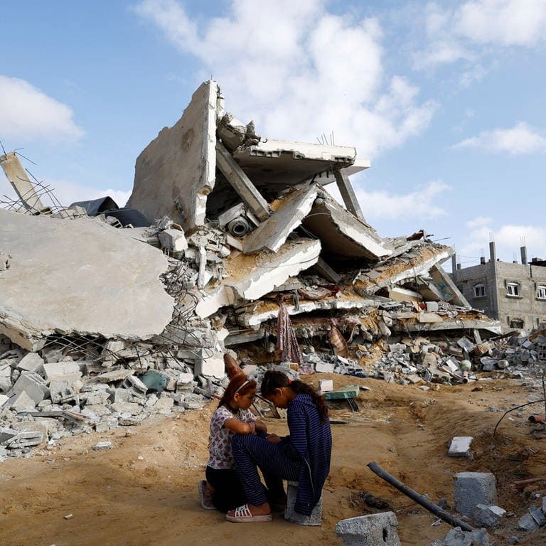 Zwei Mädchen sitzen vor einem durch einen israelischen Luftangriff zerstörten Haus in Rafah (Gazastreifen).