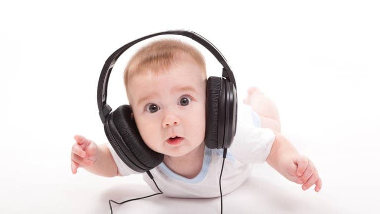 Ein niedliches Baby mit Kopfhörern ist überrascht, was es da wohl hört. Ist es vielleicht der „Happy Song“? Ein wissenschaftlich erarbeitets Kinderlied, dass Babies glücklich machen soll.