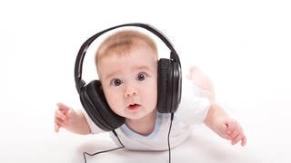 Ein niedliches Baby mit Kopfhörern ist überrascht, was es da wohl hört. Ist es vielleicht der „Happy Song“? Ein wissenschaftlich erarbeitets Kinderlied, dass Babies glücklich machen soll.