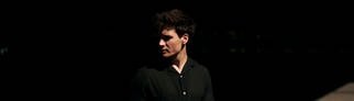 Wincent Weiss stehend mit Blick zur Seite, vor dunklem Hintergrund