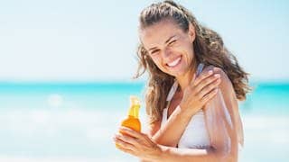 Junge Frau am Strand reibt sich mit Sonnencreme ein. Symbolbild für aktuelle Testergebnisse Stiftung Warentest zu Sonnencremes.