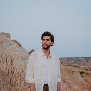 Alvaro Soler stehend in felsiger Landschaft