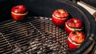 Zwischengang: Gegrillter gefüllter Apfel mit Reis auf einer grünen Salsa mit Rucola und Tomatenwürfel