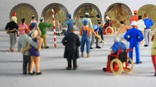 Symbolfoto Mindestlohn:Miniatur Figuren in Arbeitskleidung unterschiedlicher Branchen stehen vor Euro Geldmünzen im Wert von 8,50