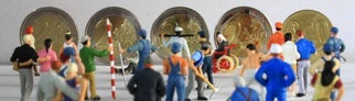 Symbolfoto Mindestlohn:Miniatur Figuren in Arbeitskleidung unterschiedlicher Branchen stehen vor Euro Geldmünzen im Wert von 8,50