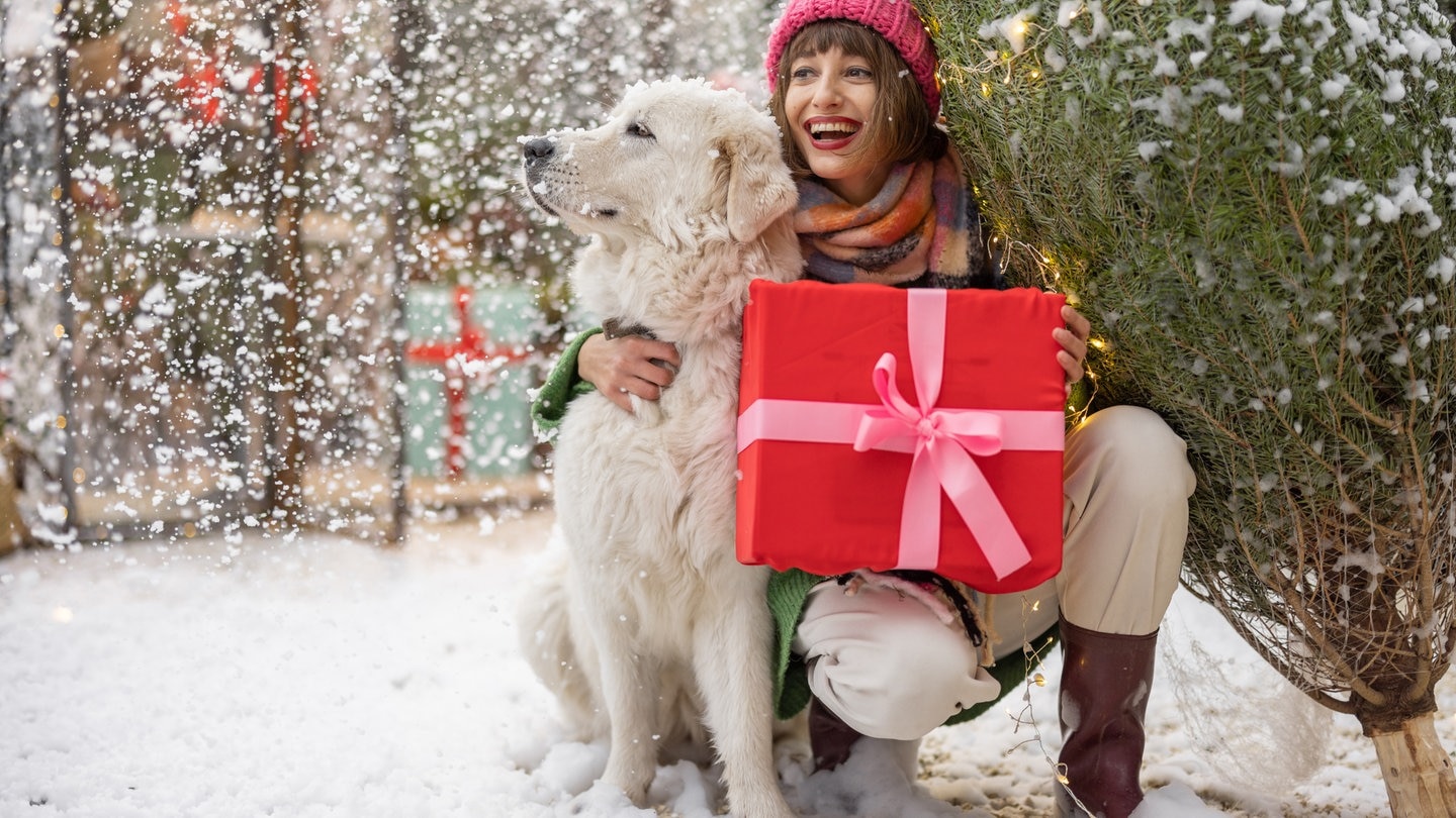 Frau steht mit Hund im Schnee | Weiße Weihnachten: Gabs das früher öfter?