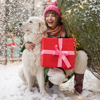 Frau steht mit Hund im Schnee | Weiße Weihnachten: Gabs das früher öfter?