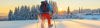 Schneeschuhwanderer läuft der Sonne entegegen