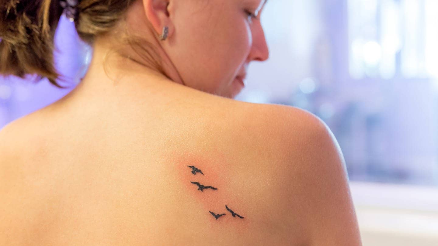 Frisches Tattoo mit fliegenden Vögeln auf dem Rücken einer jungen Frau