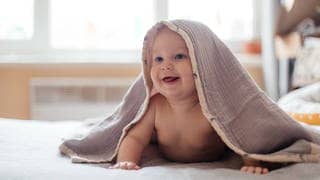 Ein Baby versteckt sich unter einer Decke