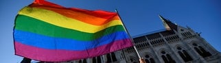 Eine Frau schwenkt eine Regenbogenfahne vor dem ungarischen Parlament