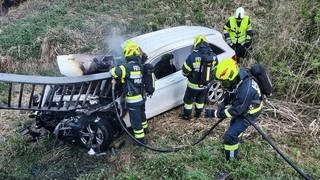 Feuerwehrleute löschen ein Auto nach einem Unfall in Österreich.