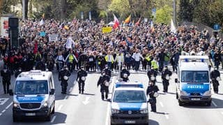 Ein Demonstrationszug der Bewegenung „Querdenken“ zieht durch Stuttgart. Polizisten sichern das Geschehen ab.