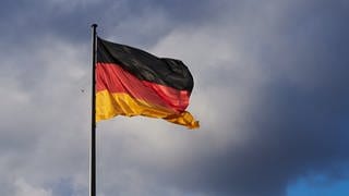 Die Abendsonne erstrahlt trotz vieler Wolken die Deutschland Flagge vor dem Reichstag. 