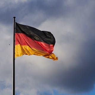 Die Abendsonne erstrahlt trotz vieler Wolken die Deutschland Flagge vor dem Reichstag. 