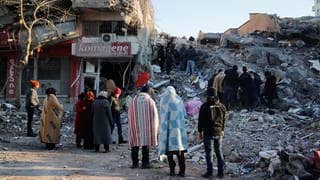 Menschen stehen vor den Trümmern eines Hauses in Kahramanmaras, Türkei.