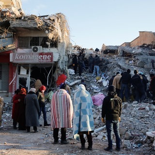 Menschen stehen vor den Trümmern eines Hauses in Kahramanmaras, Türkei.