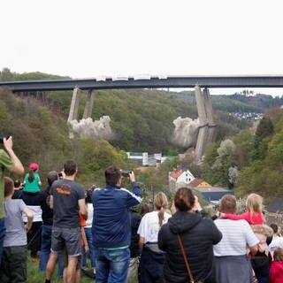 Menschen schauen aus der Ferne zu, wie die marode Rahmedetalbrücke bei Lüdenscheid gesprengt wird