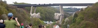 Menschen schauen aus der Ferne zu, wie die marode Rahmedetalbrücke bei Lüdenscheid gesprengt wird