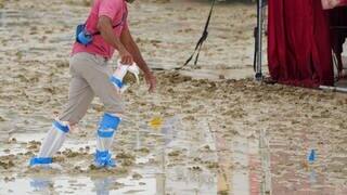 Ein Mann hat sich Plastiktüten um die Schuhe gebunden und läuft durch den Matsch beim Burning Man