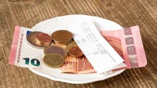 Geld liegt in einem Restaurant auf einem Teller.