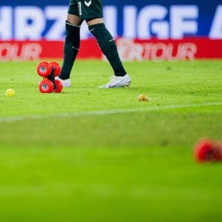 Tennisbälle und ferngesteuerte Autos liegen auf dem Spielfeld bei der Fußball-Bundesliga. Fan-Proteste legen Spiele lahm.