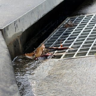 Wasser läuft einen Abwasserschacht hinunter