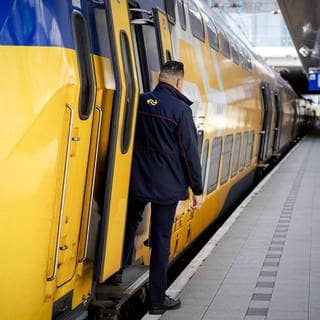 Ein Zugbegleiter schaut aus einem Zug am Bahnsteig am Bahnhof Utrecht (Niederlande)