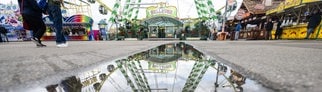 Ein Riesenrad spiegelt sich in einer Pfütze auf dem Festgelände des Stuttgarter Frühlingsfestes.