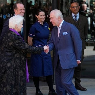 König Charles III.(M) und Königin Camilla (r) von Großbritannien werden bei ihrem Besuch im Macmillan Cancer Centre des University College Hospital begrüßt. 