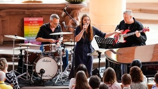 Sängerin Tine Wiechmann singt mit ihrer Band im Hintergrund in der Heiliggeistkirche während eines Taylor-Swift-Gottesdienstes.