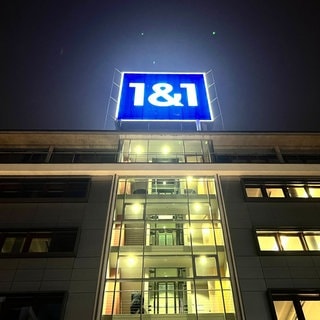 Das leuchtende Logo von 1&1 ist auf dem Dach der Firmenzentrale in Montabaur bei Nacht zu sehen.