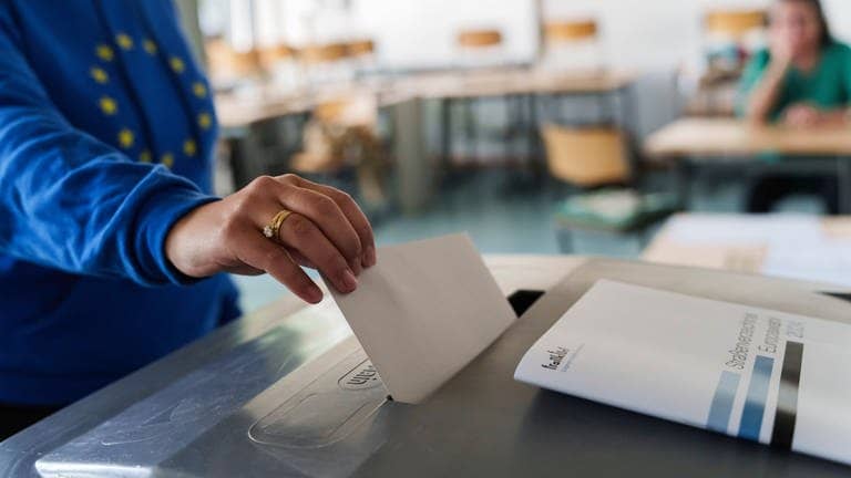 Eine Frau wirft einen Stimmzettel für die Europawahl 2024 in eine Urne.