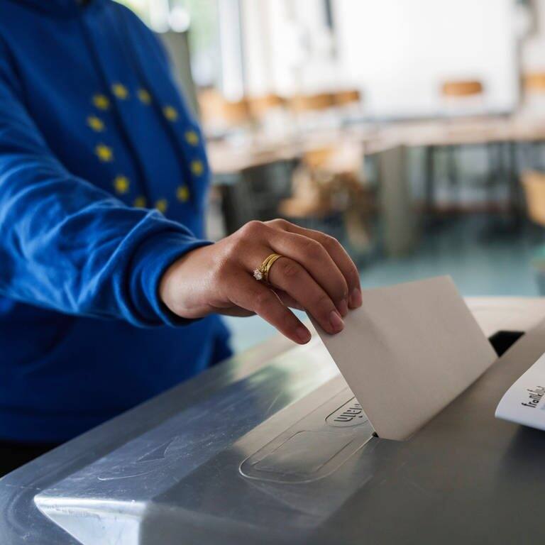Eine Frau wirft einen Stimmzettel für die Europawahl 2024 in eine Urne.