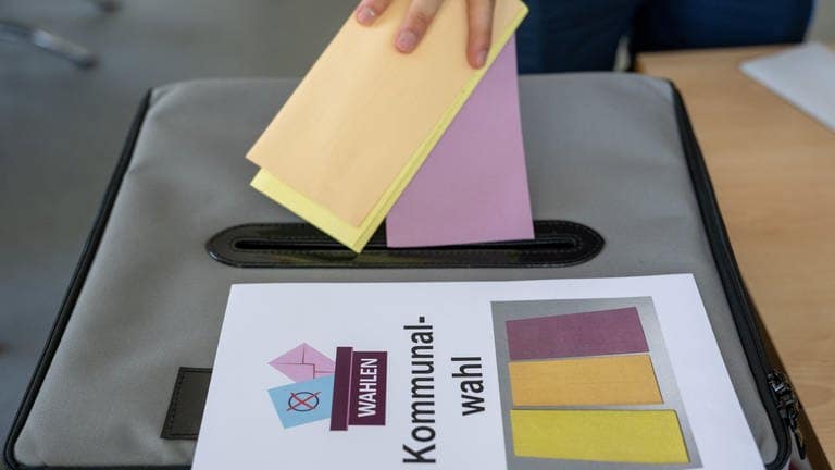 Ein Mann wirft seinen Stimmzettel zur Kommunalwahl in die Wahlurne. Zeitgleich zur Europawahl fanden in Baden-Württemberg und Rheinland-Pfalz Kommunalwahlen statt. Alles Wichtige hier!