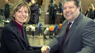 Malu Dreyer (links) und RLP-Ministerpräsident Kurt Beck schütteln sich die Hände und lächeln in die Kamera.