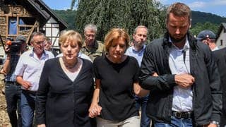 Juli 2021: Untergehakt bei der damaligen Bundeskanzlerin Angela Merkel läuft Dreyer durch das vom Hochwasser verwüstete Dorf Schuld bei Bad Neuenahr-Ahrweiler.