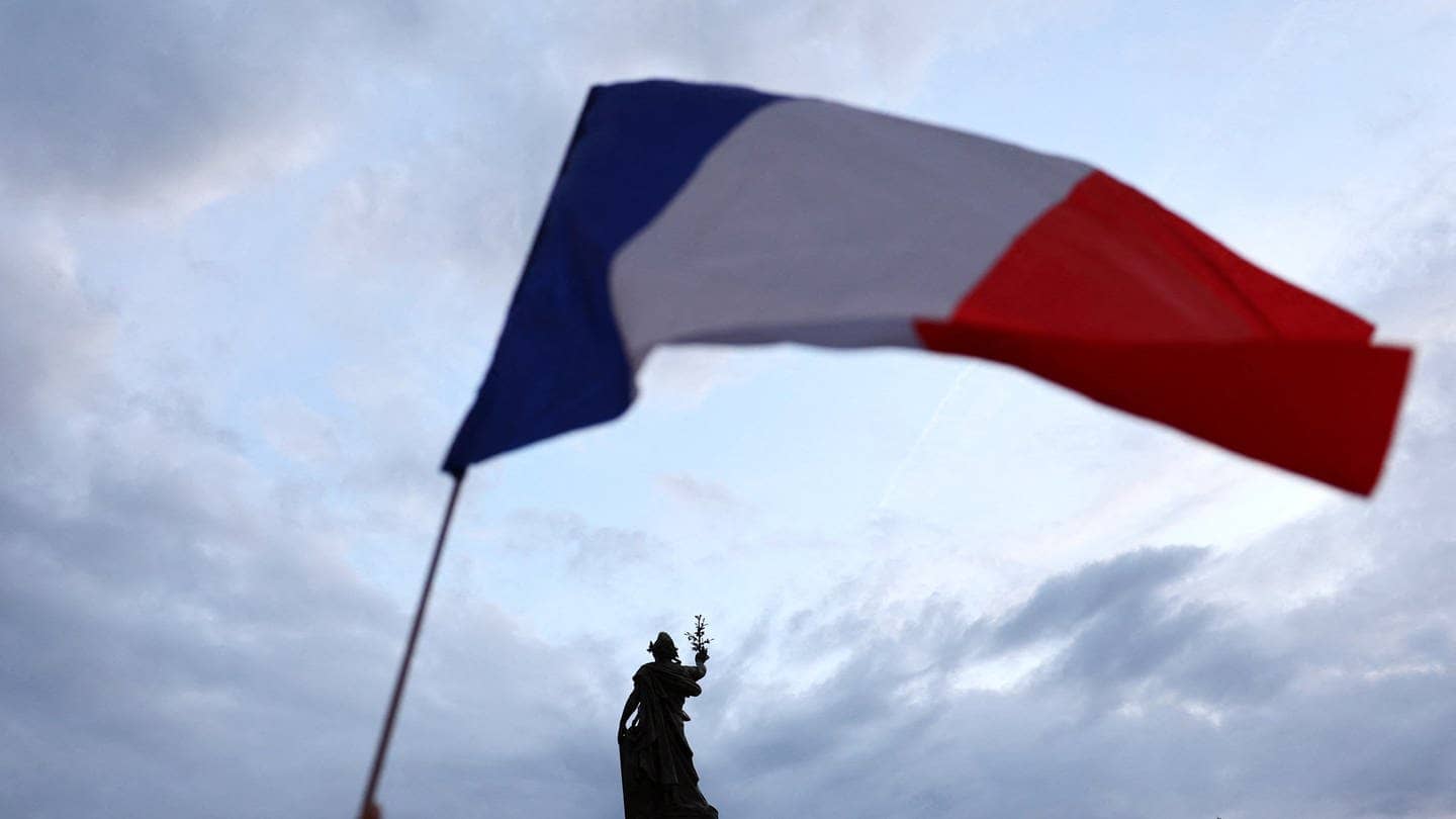 Eine französische Flagge wird vor einer Statue am Place de la Republique in Paris (Frankreich) geschwenkt