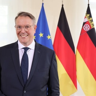 Der neue Ministerpräsident von Rheinland-Pfalz, Alexander Schweitzer (SPD), steht vor der EU-, der Deutschland- und der RLP-Flagge