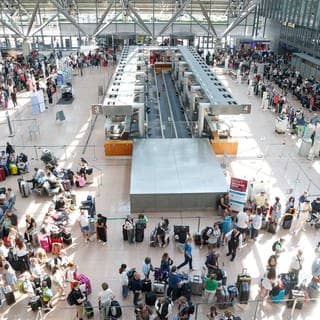 Bild von oben in die Halle: Zahlreiche Reisende warten im Terminal 1 auf die Abfertigung. 