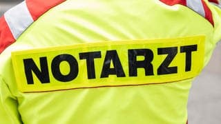 Symbolbild: Man sieht von hinten einen Notarzt der Feuerwehr mit der Aufschrift "Notarzt".