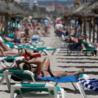 Mallorca: Menschen sonnen sich am Strand von Arenal. Palma de Mallorca will künftig die Reservierungen von Sonnenliegen am Strand mit einer App regeln.